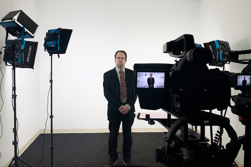 John Warren in a suit in the new film studio with camera and special lighting