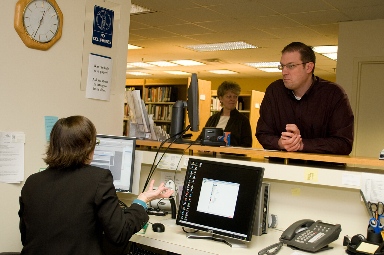 library staff talks to patrons at desk