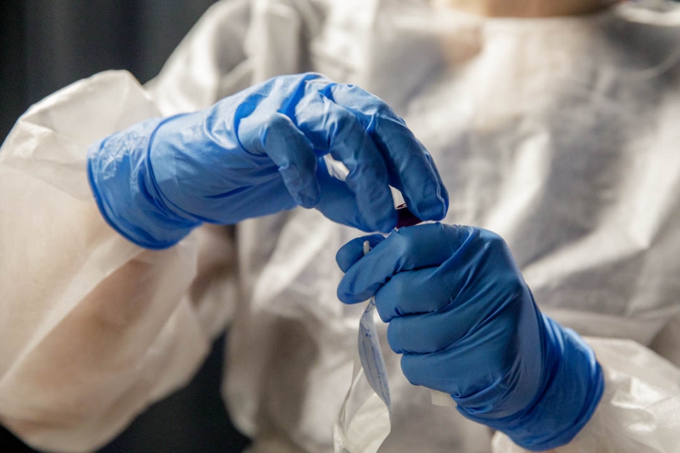 Nurse with protective white gear and blue gloves